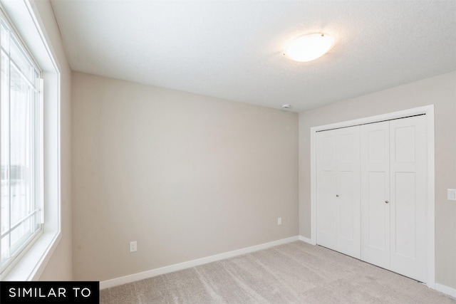 unfurnished bedroom featuring light colored carpet and a closet