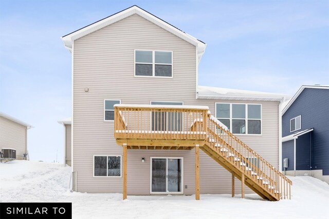 snow covered back of property with a deck and cooling unit