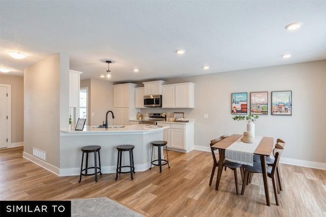 kitchen with light hardwood / wood-style floors, white cabinets, appliances with stainless steel finishes, and sink