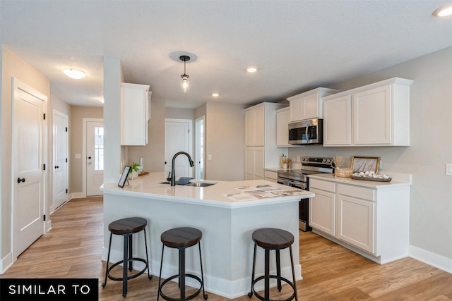 kitchen featuring stainless steel appliances, white cabinets, hanging light fixtures, and sink