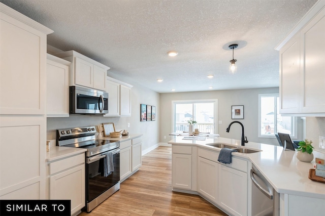 kitchen featuring a textured ceiling, white cabinets, decorative light fixtures, stainless steel appliances, and sink