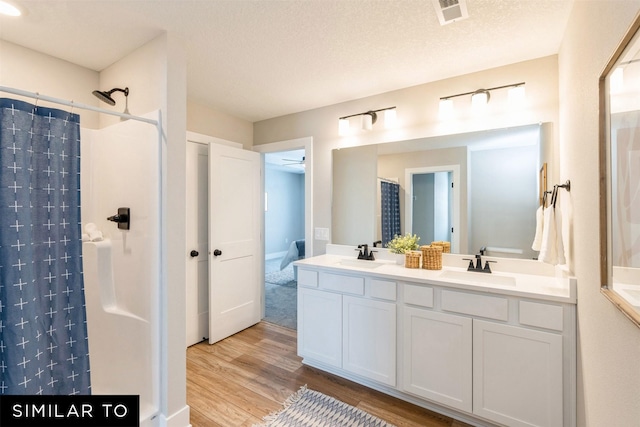 bathroom with hardwood / wood-style floors, vanity, a textured ceiling, and a shower with shower curtain