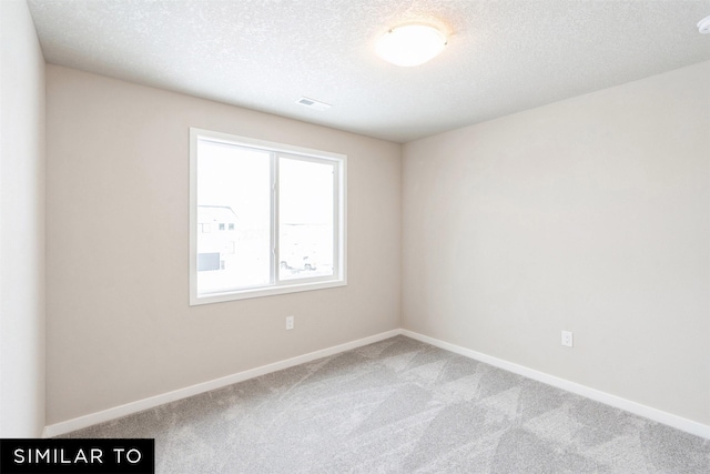 unfurnished room featuring carpet and a textured ceiling