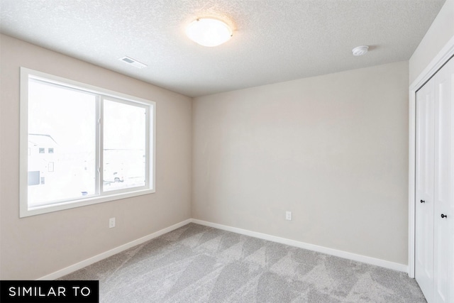 unfurnished room with a textured ceiling and light colored carpet