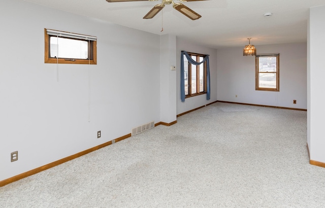 carpeted spare room featuring ceiling fan with notable chandelier