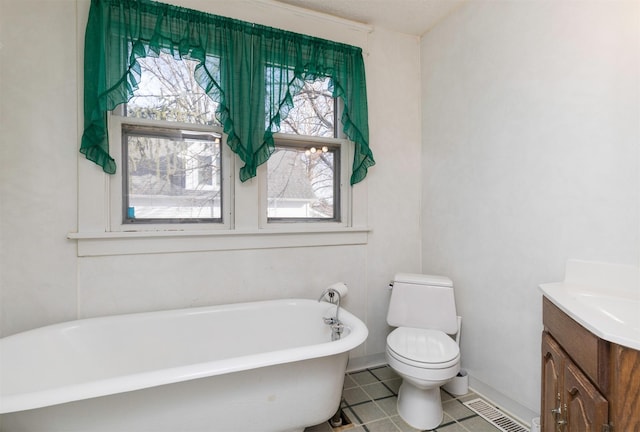 bathroom featuring toilet, tile patterned flooring, a tub, and vanity