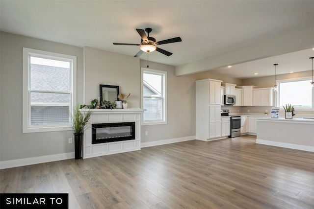 unfurnished living room with ceiling fan and hardwood / wood-style flooring