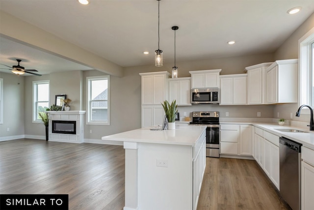 kitchen with white cabinets, appliances with stainless steel finishes, sink, and a kitchen island