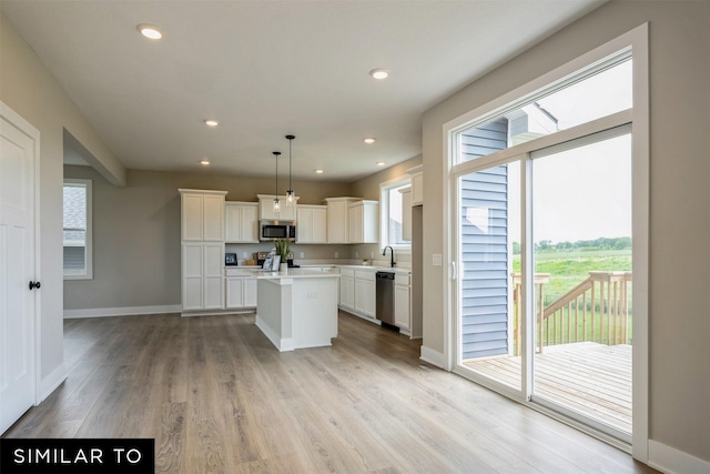 kitchen with hanging light fixtures, white cabinets, stainless steel appliances, and a kitchen island