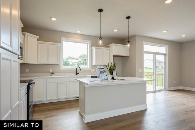 kitchen with hardwood / wood-style floors, appliances with stainless steel finishes, a kitchen island, white cabinets, and sink