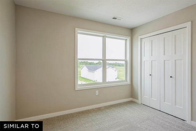 unfurnished bedroom with a closet and light carpet