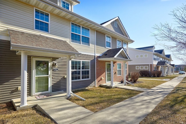 view of front of property featuring brick siding, a residential view, and roof with shingles