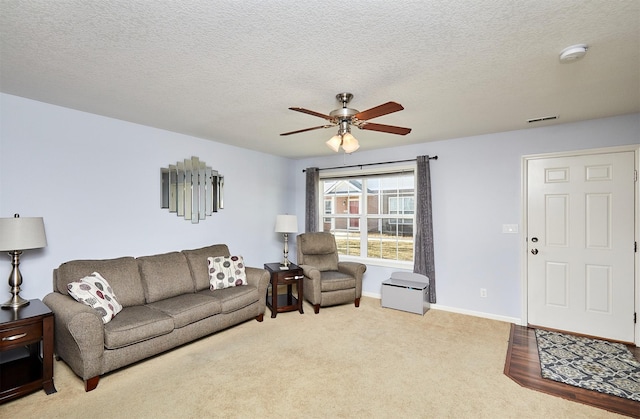 carpeted living room with visible vents, a textured ceiling, baseboards, and ceiling fan