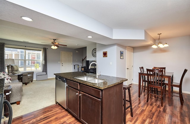 kitchen featuring dark wood-type flooring, a breakfast bar, a sink, stainless steel dishwasher, and open floor plan