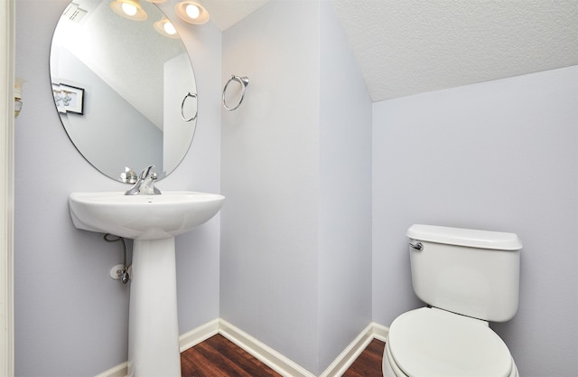 bathroom with toilet, wood finished floors, baseboards, and a textured ceiling