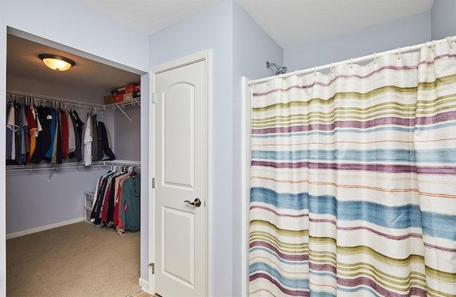 bathroom featuring a spacious closet, baseboards, and a shower with curtain