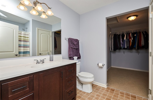 bathroom featuring a spacious closet, toilet, vanity, and baseboards