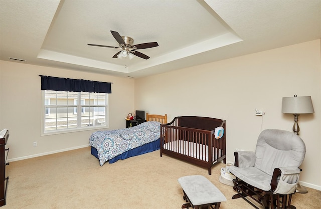 bedroom with a tray ceiling, baseboards, ceiling fan, and carpet flooring