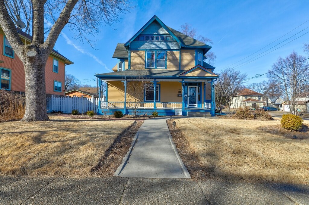 victorian home featuring covered porch and a front lawn