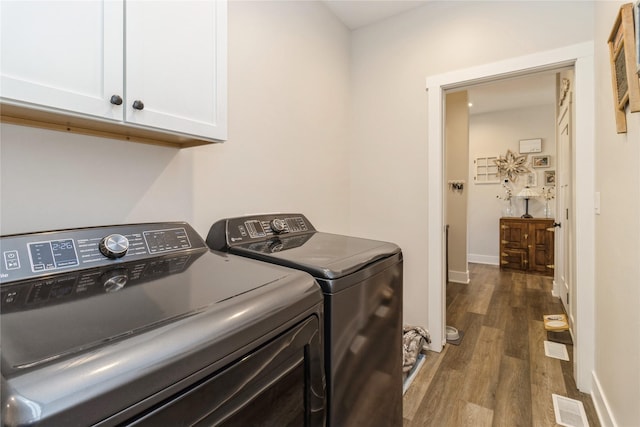 laundry room featuring dark wood-type flooring, cabinets, and washing machine and clothes dryer