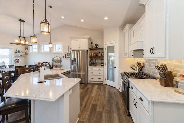 kitchen featuring a large island, stainless steel appliances, lofted ceiling, hanging light fixtures, and white cabinets