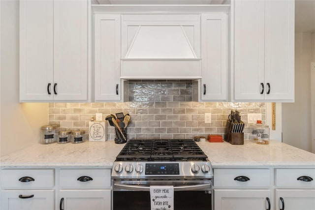 kitchen with stainless steel range with gas cooktop, white cabinetry, premium range hood, and tasteful backsplash