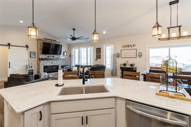 kitchen with stainless steel dishwasher, a barn door, decorative light fixtures, and sink