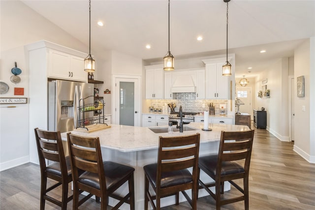 kitchen with decorative light fixtures, stainless steel refrigerator with ice dispenser, vaulted ceiling, and white cabinetry