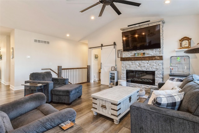 living room with vaulted ceiling, dark wood-type flooring, a barn door, and ceiling fan