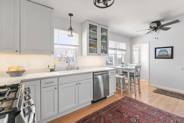 kitchen featuring decorative light fixtures, sink, white cabinetry, light hardwood / wood-style flooring, and stainless steel appliances