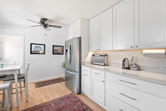 kitchen featuring ceiling fan, white cabinets, light wood-type flooring, and stainless steel refrigerator