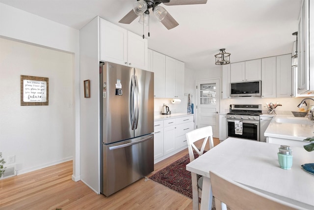 kitchen with white cabinets, sink, stainless steel appliances, and light hardwood / wood-style floors