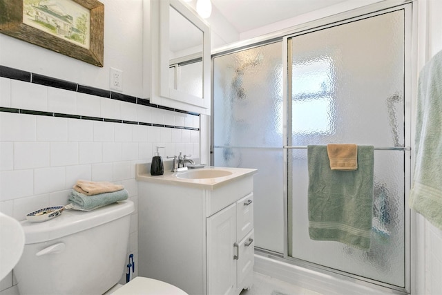 bathroom featuring toilet, vanity, tile walls, and an enclosed shower