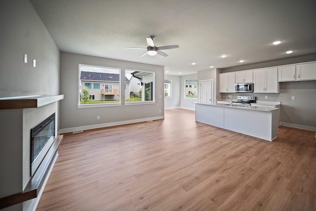 503 43rd St SW, Altoona, IA 50009 - kitchen with stainless steel appliances, white cabinetry, recessed lighting, a ceiling fan, and a fireplace