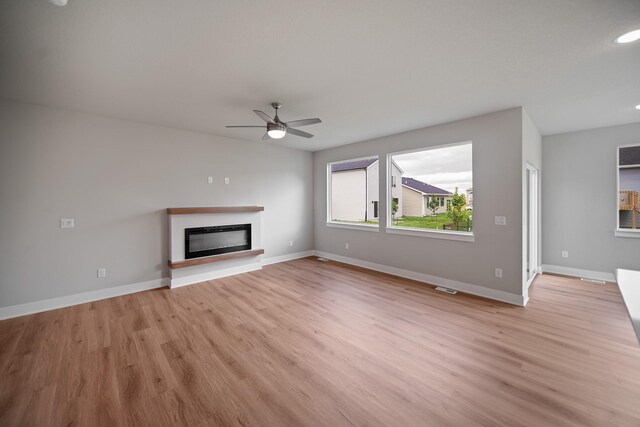503 43rd St SW, Altoona, IA 50009 - unfurnished living room featuring light wood-type flooring, ceiling fan, a glass covered fireplace, baseboards, and recessed lighting