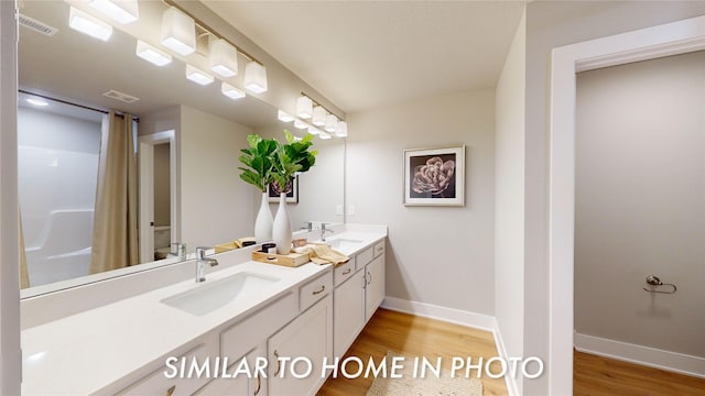 bathroom with toilet, vanity, and wood-type flooring