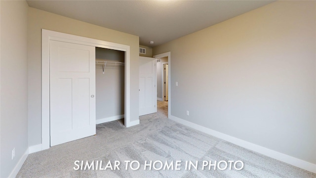 unfurnished bedroom with light carpet and a closet