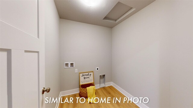 laundry area with a textured ceiling, electric dryer hookup, hookup for a washing machine, and hardwood / wood-style flooring