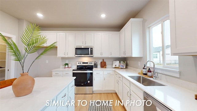 kitchen featuring appliances with stainless steel finishes, sink, white cabinetry, and plenty of natural light