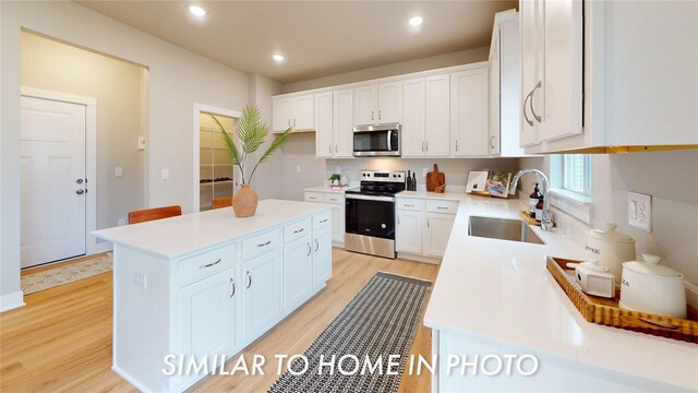 kitchen with white cabinetry, appliances with stainless steel finishes, a center island, and light wood-type flooring