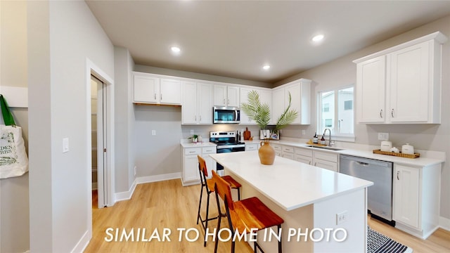 kitchen with a center island, sink, white cabinetry, a breakfast bar area, and stainless steel appliances