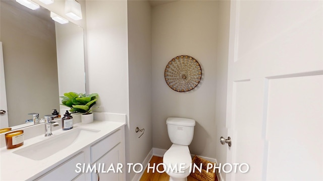 7046 SE 7th Ave, Pleasant Hill, IA 50327 - bathroom with baseboards, wood finished floors, toilet, and vanity