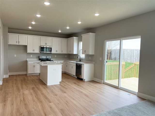 7046 SE 7th Ave, Pleasant Hill, IA 50327 - kitchen with visible vents, stainless steel appliances, a kitchen island, baseboards, and light wood-type flooring