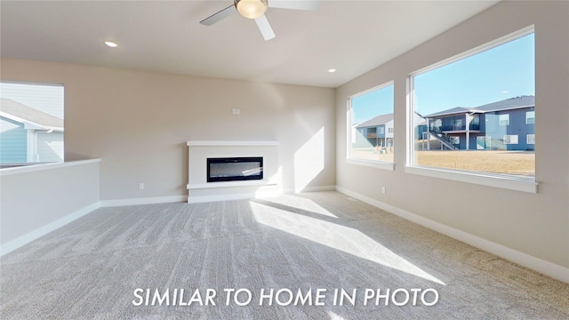 unfurnished living room with light carpet, a wealth of natural light, and ceiling fan