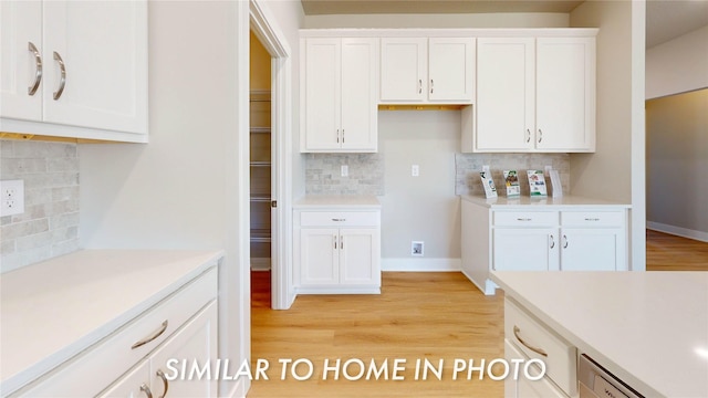 kitchen with tasteful backsplash, white cabinetry, dishwasher, and light hardwood / wood-style flooring