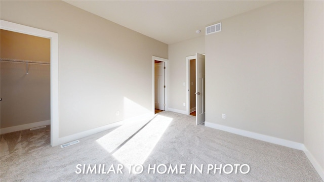 unfurnished bedroom featuring a walk in closet and light colored carpet