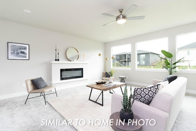 living area with ceiling fan, carpet floors, a glass covered fireplace, and baseboards