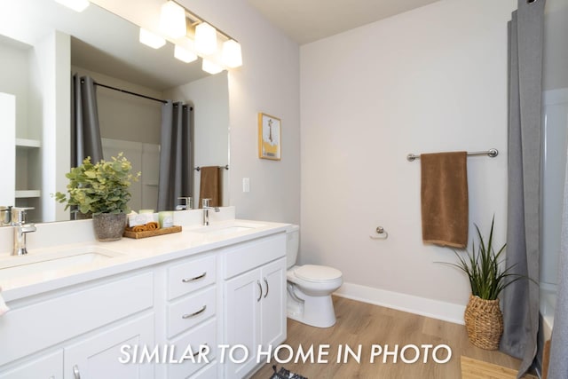 bathroom with wood finished floors, a sink, double vanity, and toilet