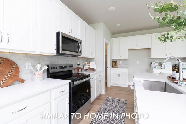 kitchen with white cabinets, light countertops, appliances with stainless steel finishes, and a sink