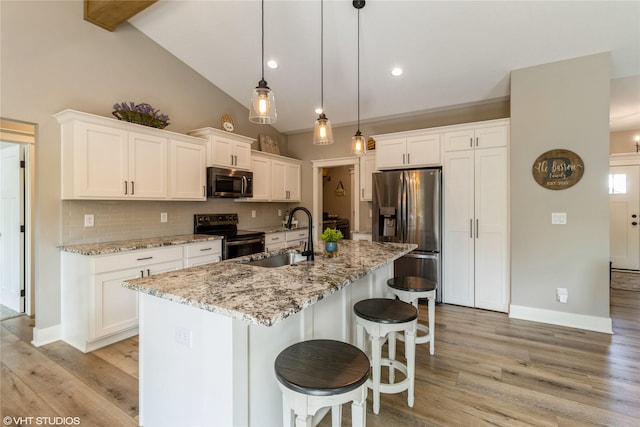 kitchen with appliances with stainless steel finishes, white cabinetry, decorative backsplash, sink, and a center island with sink